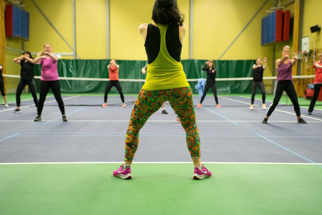 Zumbainstruktör i träningskläder med deltagare framför sig